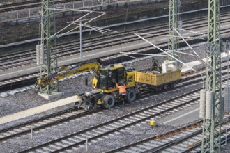 A construction site scene with yellow excavator and wagon near railroad tracks, Untertürkheim