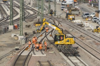 Rail construction with a group of workers and a yellow construction machine vehicle on the