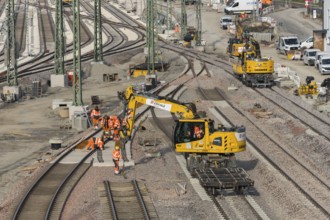 Track construction on a construction site with groups of construction workers and a yellow