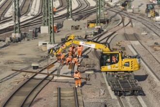 Workers wearing protective clothing carry out construction work on a railway construction site,