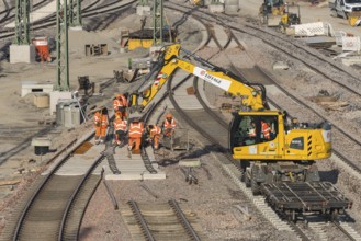 Construction workers wearing orange safety clothing during track repairs on a construction site,