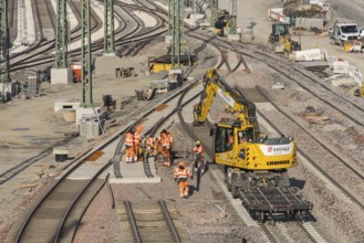 Rail construction workers wearing safety clothing at work next to a large machine, Untertürkheim