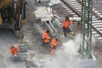 Construction workers in protective clothing carry out work on rails, accompanied by construction