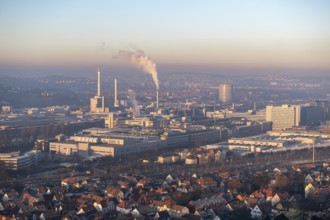 Aerial view of a city at dusk, with industrial structures and suburban houses, sky and smoke
