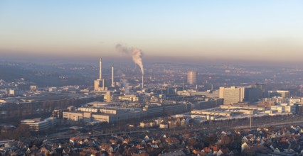 Extensive city view at sunrise with industrial plants and smoke developments, view of Daimler Group