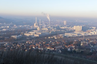 View of a city in morning light with industrial buildings and smoke from chimneys, Daimler