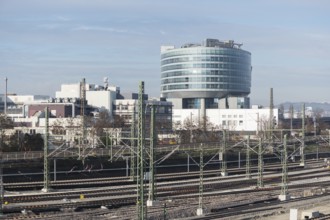 Modern building in an industrial area with railroad tracks in the foreground under clear skies,