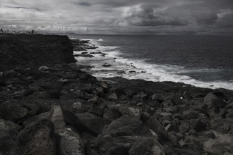 Dramatic, cloudy coastal scene with rough rocks and a wavy sea. Dark, stormy atmosphere, Yaiza