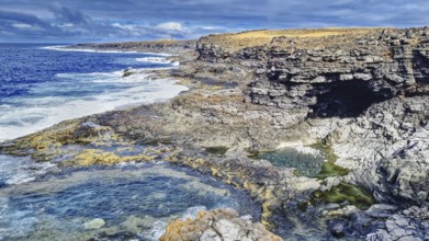 Rugged coastal landscape with rocks and a grotto. Waves hit the rocky shoreline, Yaiza Lanzarote