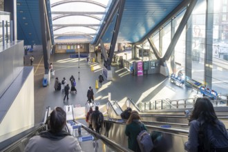 People on escalator of modern architecture of railway station concourse building, Reading,