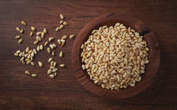 Peeled pine nuts, in a wooden bowl, on a wooden table, close-up, no people