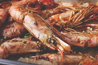 Juicy grilled shrimp, placed on a baking sheet lined with parchment paper, garnished with herbs and