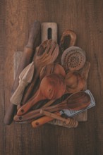 Various wooden kitchen utensils, including spoons, a rolling pin, and a strainer, are artistically