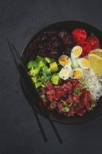 Fresh poke bowl with tuna, avocado, and vegetables served on a black plate