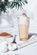 Eggnog drink, egg yolk, in a glass, with cream and cinnamon, sunlight