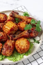 Fried chicken drumsticks, Mexican style, with corn, on a plate, close-up