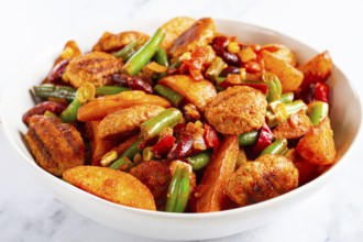 Steakhouse pfanne, fried potato slices, with meatballs, and vegetable mixture, on a white plate