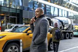 Businessman using a mobile phone on a bustling manhattan street, communicating while cars,