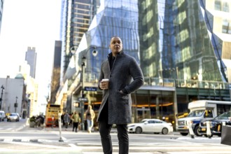 Confident businessman standing on a manhattan street with hand in a modern coat pocket, holding a