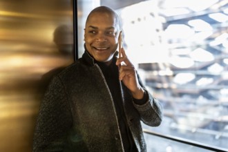 Smiling professional man engaging in a phone conversation, using a smartphone while standing