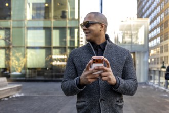 Professional black man smiling in a stylish gray jacket and sunglasses, walking manhattan streets