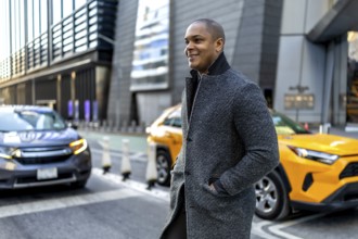 Happy young businessman walking through a busy downtown manhattan street, wearing a stylish gray