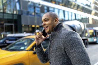 Young black businessman is walking on a city street in manhattan, new york, laughing while having a