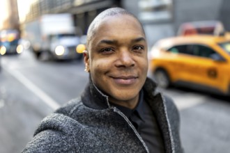 Happy african american businessman standing on a busy new york city street with blurred taxis and