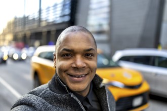 Smiling african american businessman taking a selfie on a vibrant city street, showcasing a