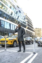 Professional man having a mobile phone conversation on a city street, standing confidently amidst