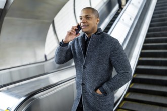 Young businessman talking on his smartphone while traveling on an escalator in a manhattan subway