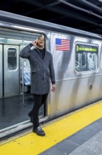 Happy professional man smiling and talking on smartphone while stepping onto a manhattan subway