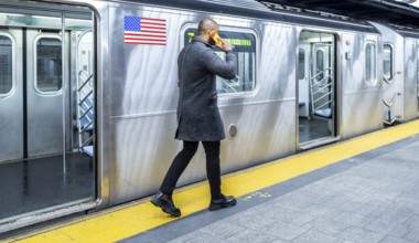 Man walking on the subway platform, talking on a mobile phone while waiting to board a train,