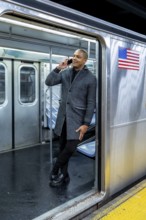 Young man standing confidently in a subway car doorway, talking on his smartphone, representing