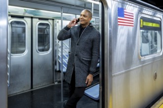Smiling businessman traveling on a new york city subway train, talking on a mobile phone,
