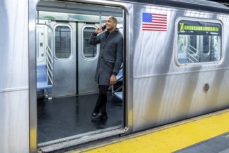 Young man in a stylish coat smiling and talking on his smartphone while standing at the open doors