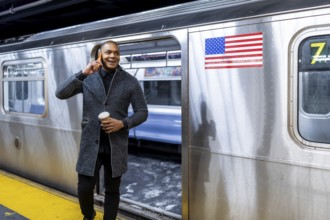 Young businessman commuting in new york city, holding a cup of coffee and having a conversation on