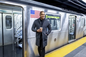 African american professional standing on a manhattan subway platform holding a coffee cup and