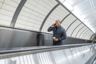 Businessman navigating urban commute on an escalator while engaged in a mobile phone conversation,