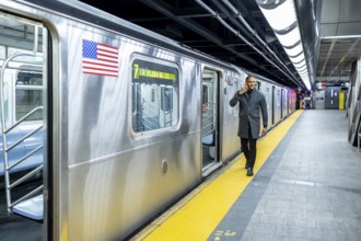 Professional businessman smiling and talking on his phone while exiting a manhattan subway train,