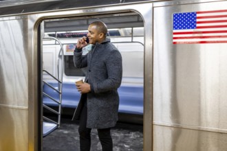 Man holding a coffee cup and having a conversation on his mobile phone, standing inside a new york