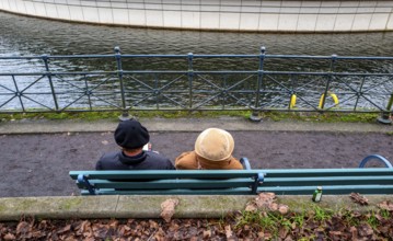 Senior couple sitting on a park bench at the Tegel harbor basin, Berlin, Germany
