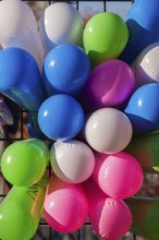 Close-up of colourful balloons inflated with helium gas and attached to black metal lattice support