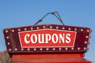 Close-up of the word coupons spelled out in bold white letters on red and maroon colored banner,