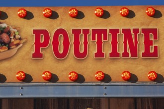Close-up of the word Poutine spelled out in bold red letters on tan colored banner, Quebec, Canada