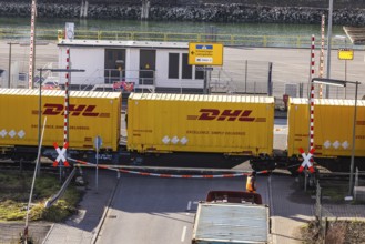 Freight train loaded with yellow container from DHL. Railway crossing in the port area of Mannheim,