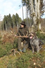 Huntress with a deer (Cervus elaphus) hunting dog Griffon at her side, Allgäu, Bavaria, Germany,