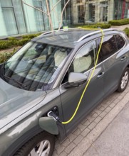 An e-car is charged at a charging station in Düsseldorf, the charging cable is stored over the roof