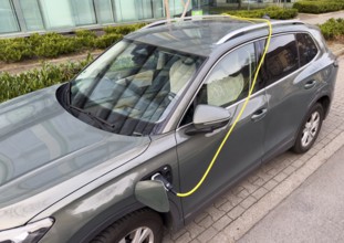 An e-car is charged at a charging station in Düsseldorf, the charging cable is stored over the roof