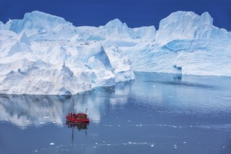 Aerial view of a tourist ship navigating through the fjord among icebergs calved from the